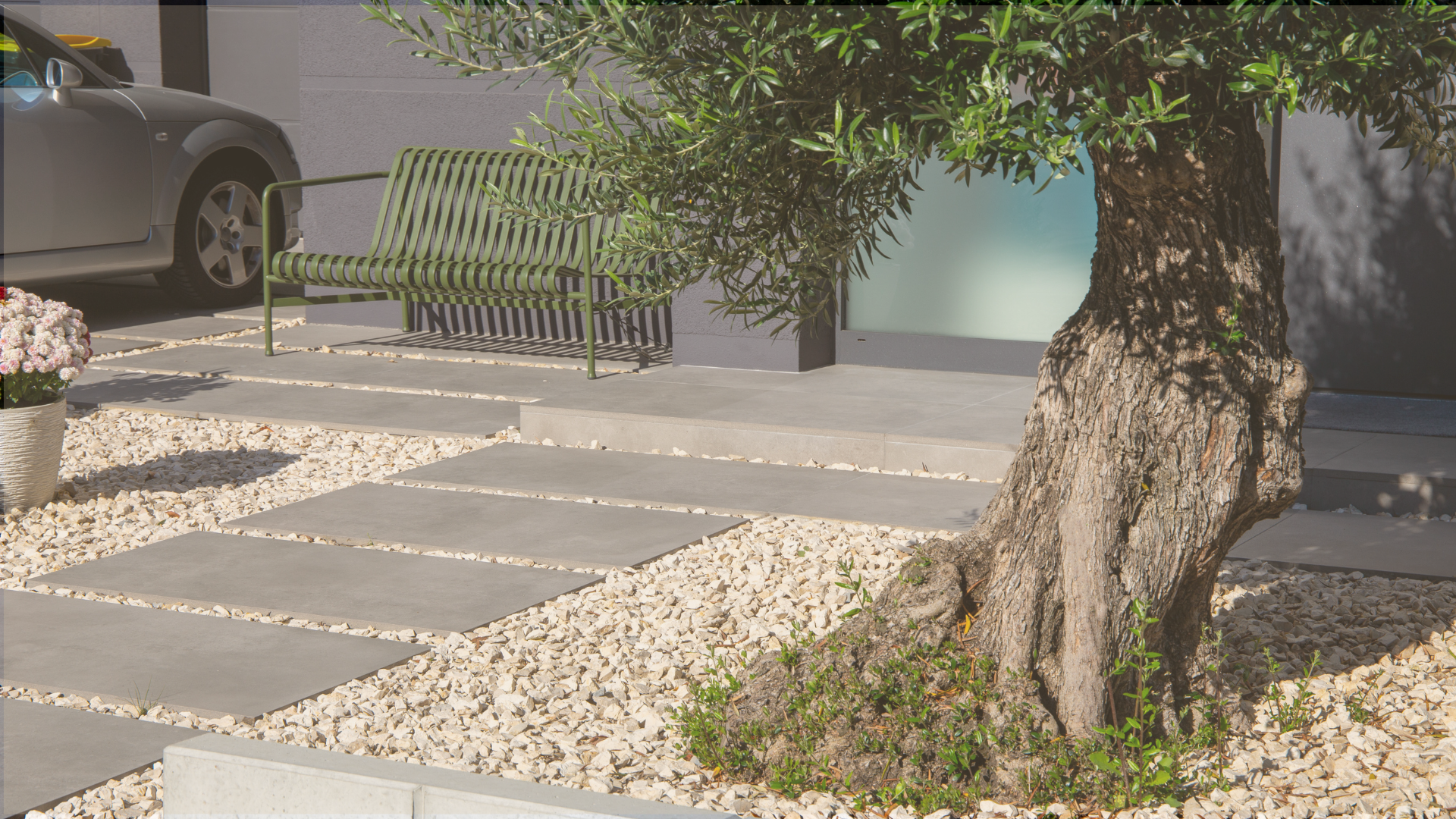 Einfahrt mit Bodenplatten, Splitt und einem Olivenbaum